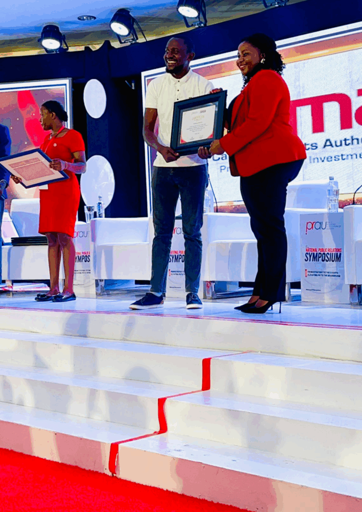 Newman's representative accepts an award from PRAU on stage at the National PR Symposium.