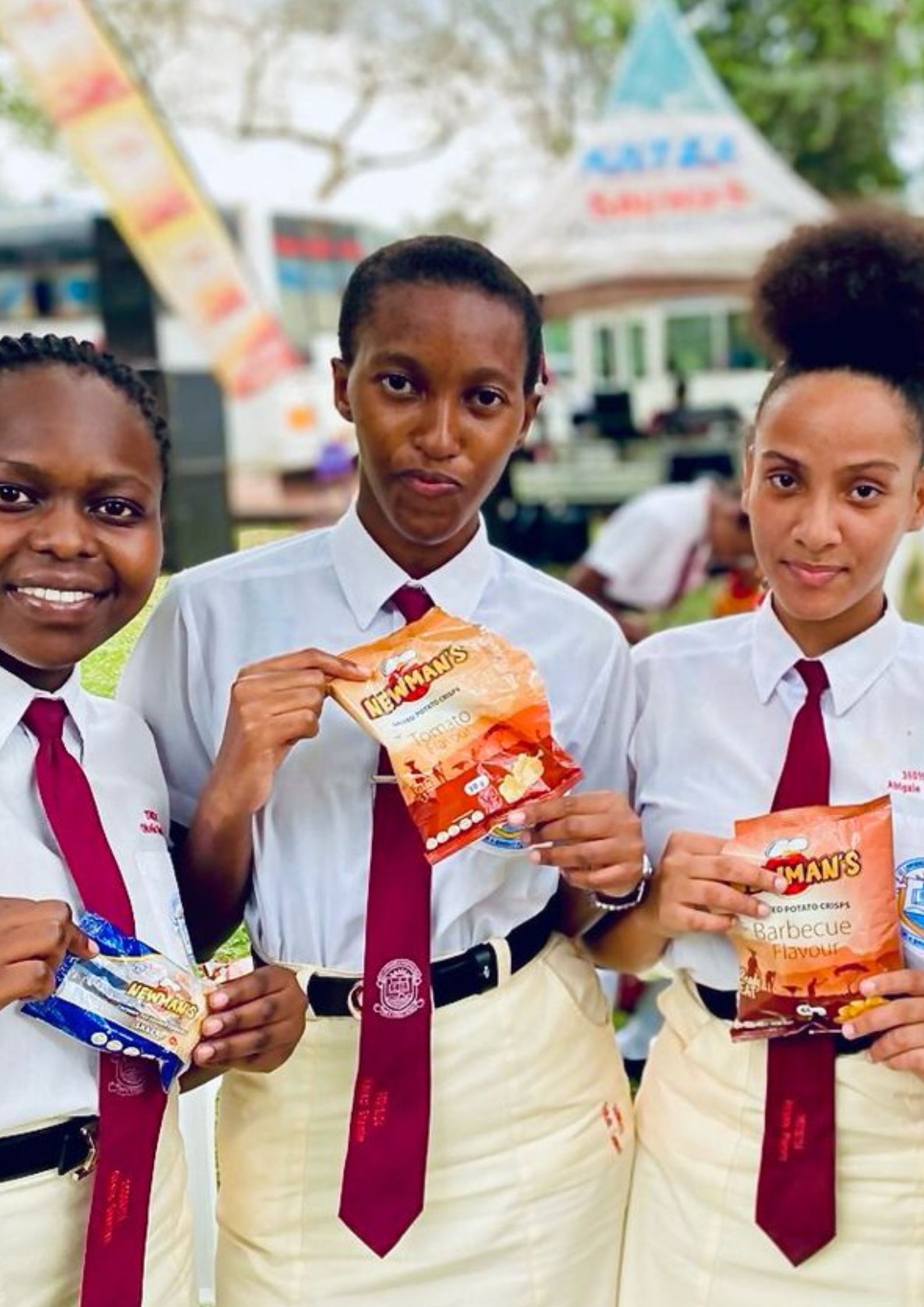 A group of three students in school uniform eating Newman's snacks