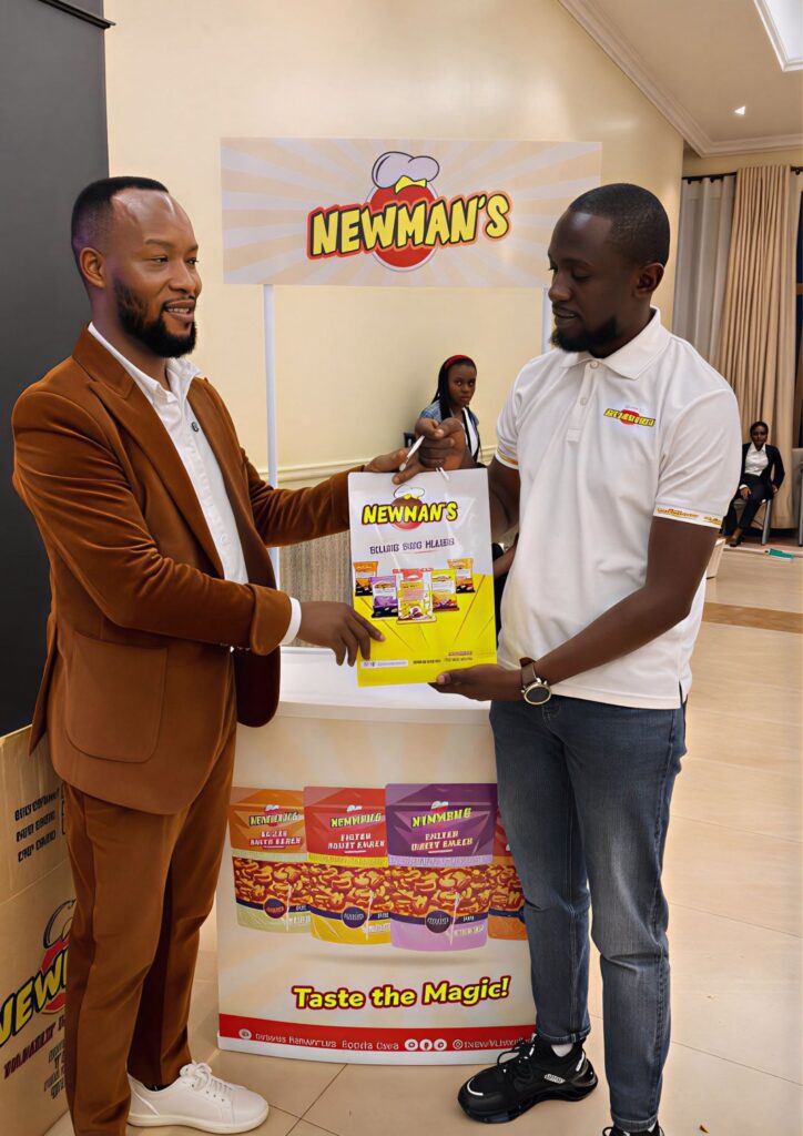 A Newman;s representative handing over a Newman's bag to a man dressed in a brown suit at the KAMOSA Annual Dinner 2025
