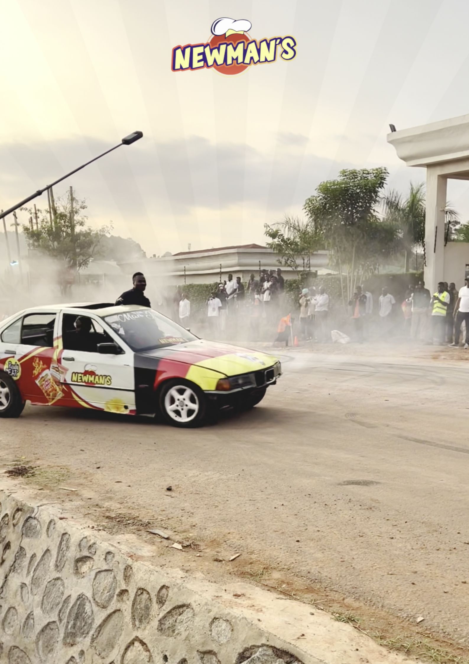 Newman's branded Rally car doing a smoke-filled burnout with spectators in the background